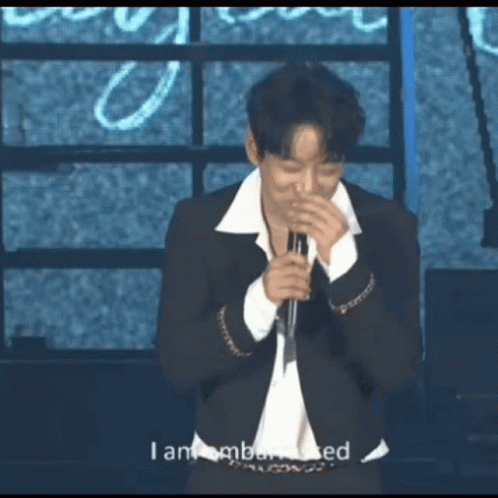 A Man Singing Into A Microphone With The Words I Am Embarrassed Behind Him GIF