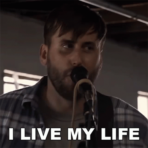 A Man Singing Into A Microphone With The Words I Live My Life Above Him GIF
