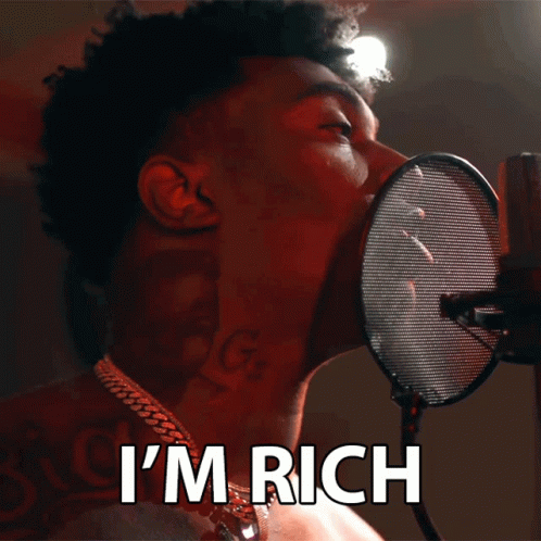 A Man Singing Into A Microphone With The Words I 'M Rich Behind Him GIF