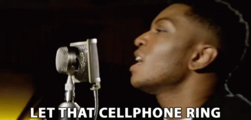 A Man Singing Into A Microphone With The Words Let That Cellphone Ring Behind Him GIF