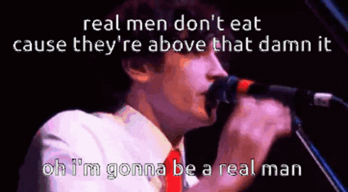 A Man Singing Into A Microphone With The Words " Real Men Don 'T Eat Cause They 'Re Above That Damn It " GIF