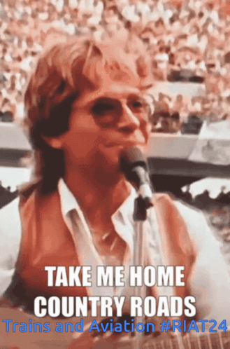 A Man Singing Into A Microphone With The Words Take Me Home Country Roads Above Him GIF