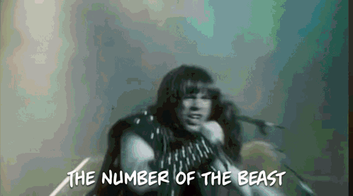 A Man Singing Into A Microphone With The Words " The Number Of The Beast " Above Him GIF