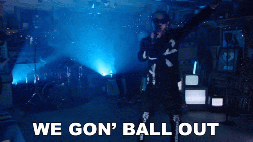 a man singing into a microphone with the words " we gon ' ball out " behind him