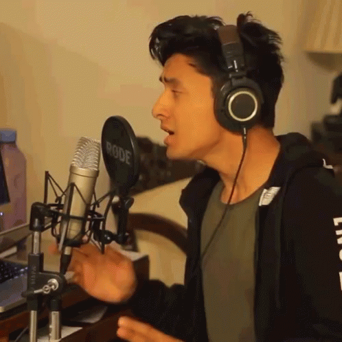 A Man Singing Into A Rode Microphone With Headphones On GIF
