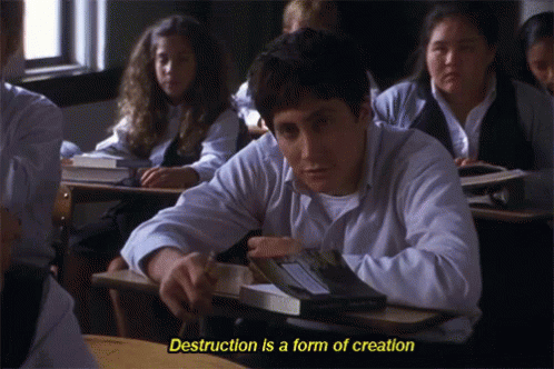A Man Sits At A Desk In A Classroom With The Words " Destruction Is A Form Of Creation " Above Him GIF