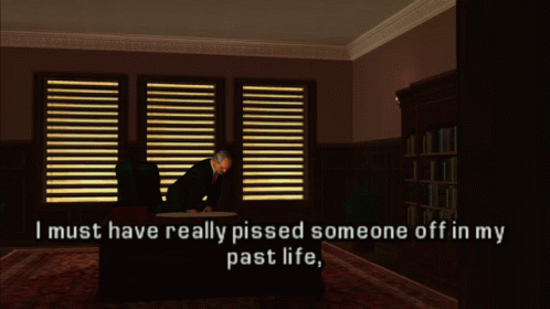 A Man Sits At A Desk In A Dark Room With The Words " I Must Have Really Pissed Someone Off In My Past Life " GIF