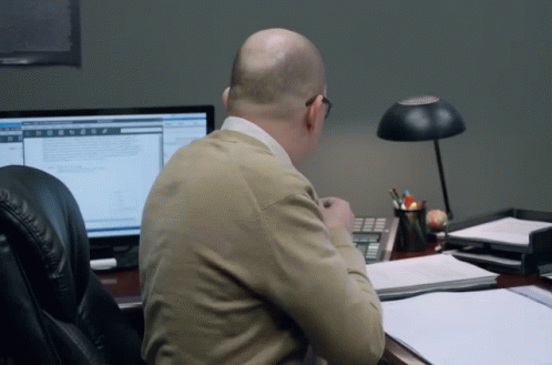 A Man Sits At A Desk In Front Of A Computer Screen GIF