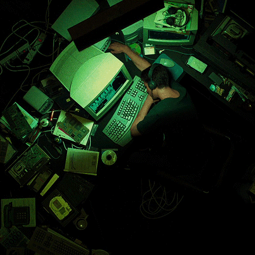 A Man Sits At A Desk With A Computer And A Keyboard That Says " Microsoft " On It GIF