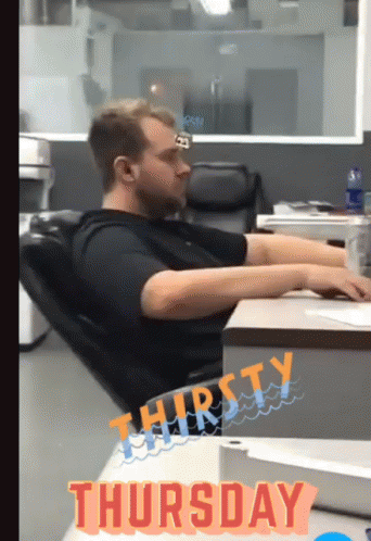 A Man Sits At A Desk With The Word Thursday On The Bottom GIF
