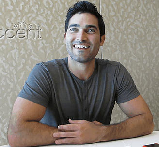 A Man Sits At A Table In Front Of A Wall That Has The Word Accent On It GIF
