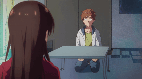 A Man Sits At A Table With A Woman Looking At Him GIF