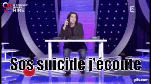A Man Sits At A Table With The Words Sos Suicide J'écoute Written On The Screen GIF