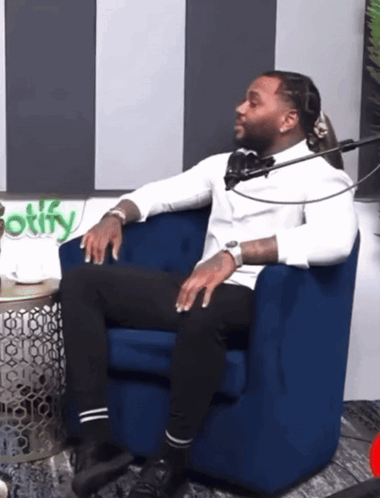 A Man Sits In A Blue Chair In Front Of A Spotify Logo GIF