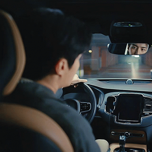 A Man Sits In A Car Looking At The Rear View Mirror GIF