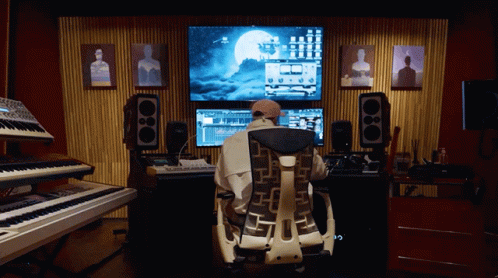 A Man Sits In A Chair In Front Of A Computer Screen With A Full Moon On It GIF
