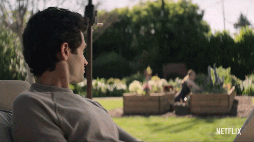 A Man Sits In A Chair In Front Of A Netflix Sign GIF