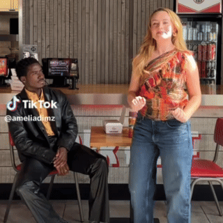 A Man Sits In A Chair While A Woman Stands In Front Of Him With A Tiktok Watermark GIF