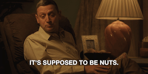 A Man Sits In A Chair With The Words It 'S Supposed To Be Nuts GIF