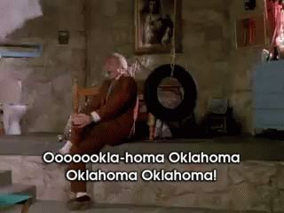 A Man Sits In A Chair With The Words Oklahoma Oklahoma Written On The Bottom GIF