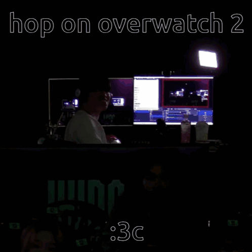 A Man Sits In Front Of A Computer Screen With The Words Hop On Overwatch 2 Written Above Him GIF
