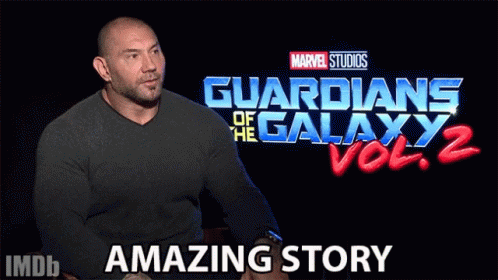 A Man Sits In Front Of A Guardians Of The Galaxy Vol 2 Sign GIF