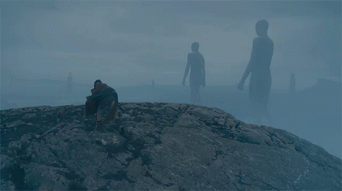 A Man Sits On A Rock In Front Of A Group Of Giant Silhouettes GIF