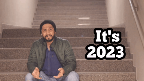 A Man Sits On A Set Of Stairs With The Words " It 'S 2023 " On The Bottom GIF