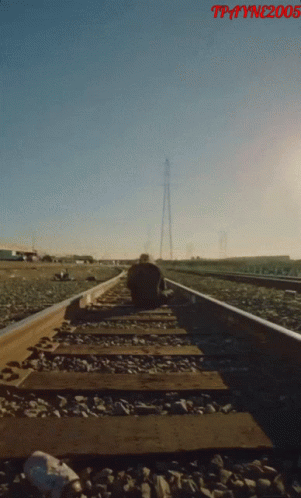 A Man Sits On A Train Track With The Year 2005 On The Bottom Right GIF