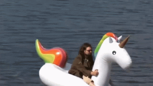 A Man Sits On An Inflatable Unicorn Floating In The Water GIF