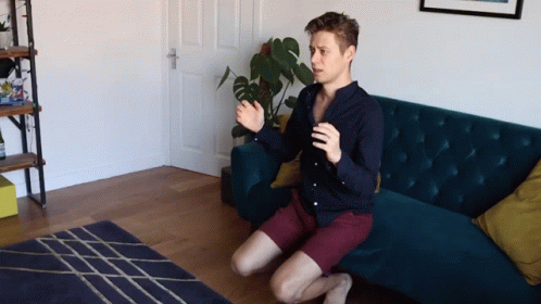 a man sits on his knees in front of a couch