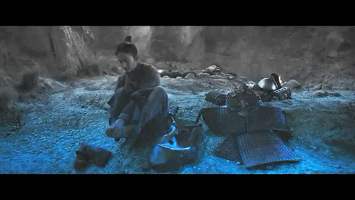 A Man Sits On The Ground In A Dark Cave GIF