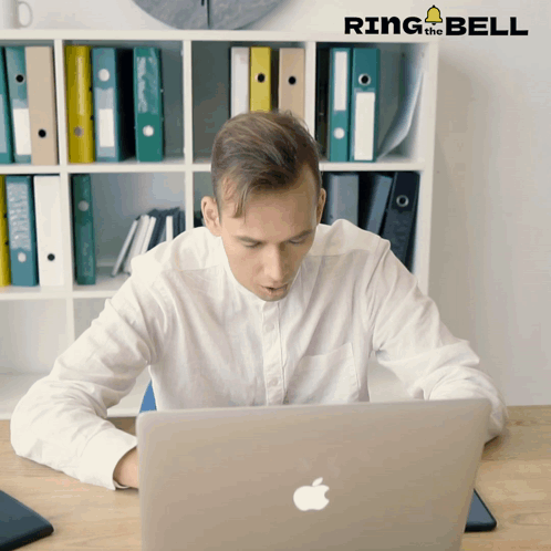 A Man Sitting At A Desk Looking At A Laptop With Ring The Bell Written On The Bottom GIF