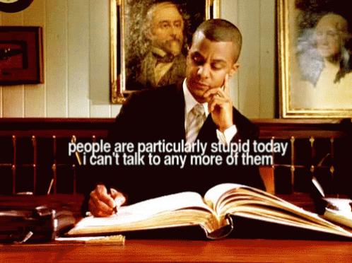 A Man Sitting At A Desk Reading A Book With The Words People Are Particularly Stupid Today GIF