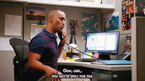 A Man Sitting At A Desk Talking On A Phone With The Words Ooh Girl You Gotta Spill The Tea GIF