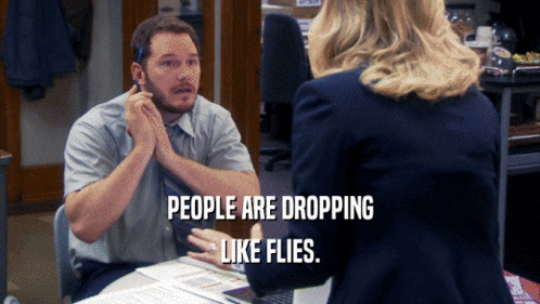A Man Sitting At A Desk Talking To A Woman With The Words People Are Dropping Like Flies Above Him GIF