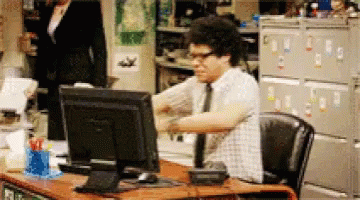 A Man Sitting At A Desk With A Computer Monitor GIF