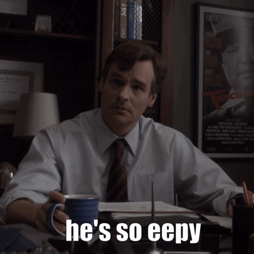 A Man Sitting At A Desk With A Cup Of Coffee And The Words He 'S So Eepy On The Bottom GIF