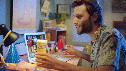 A Man Sitting At A Desk With A Laptop And A Glass Of Pabst Beer In Front Of Him GIF
