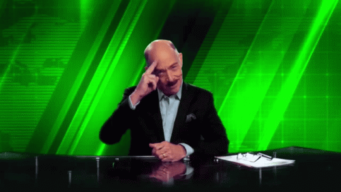 A Man Sitting At A Desk With His Hand On His Forehead GIF