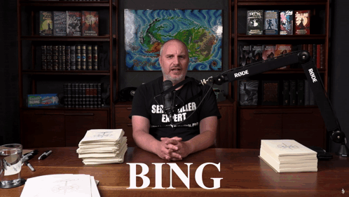 A Man Sitting At A Desk With The Word Bing On The Top GIF