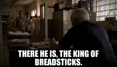 A Man Sitting At A Desk With The Words " There He Is The King Of Breadsticks " GIF