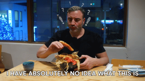 A Man Sitting At A Table Eating Food With The Words I Have Absolutely No Idea What This Is GIF