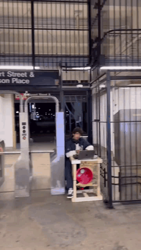 A Man Sitting At A Table In Front Of A Sign That Says Street And Son Place GIF