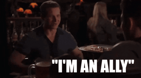 a man sitting at a table says " i 'm an ally " while talking to another man
