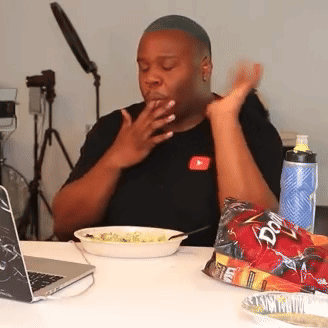 a man sitting at a table with a bag of doritos next to him