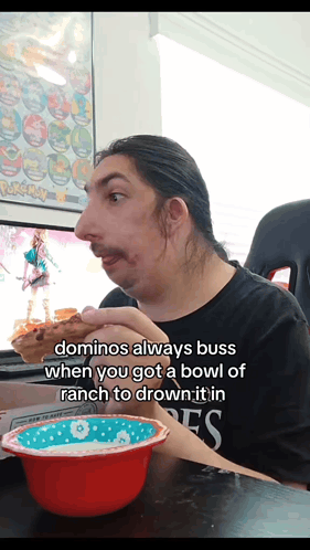 a man sitting at a table with a bowl of ranch and a bowl of domino 's