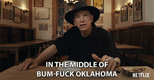 A Man Sitting At A Table With A Cigarette In His Hand Says In The Middle Of Bum-Fuck Oklahoma Netflix GIF