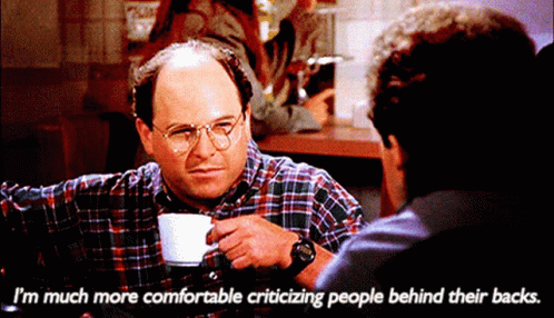 A Man Sitting At A Table With A Cup Of Coffee Says I 'M Much More Comfortable Criticizing People GIF