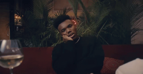 A Man Sitting At A Table With A Glass Of Wine GIF